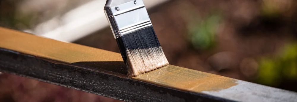 Pinsel trägt goldene Farbe auf Metall auf